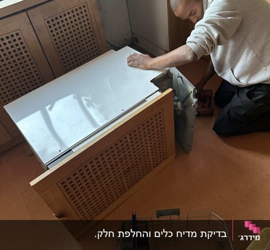 אדם מתקן מדיח כלים במטבח